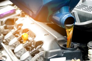 Mechanic pouring oil into a car engine. Choosing the best engine oil is important for truck maintenance.