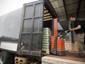 Truck driver using pallet jack to load goods onto truck, illustrating key truck driver duties in load securement.