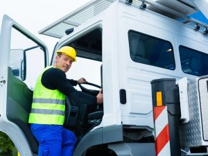 Truck driver in safety vest and helmet entering cab, demonstrating truck driver duties related to vehicle operation and safety.