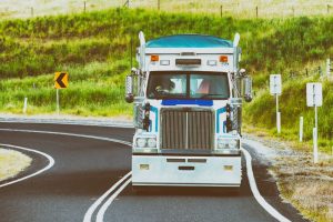 Truck driver fatigue: A large white truck drives on a winding road, highlighting the risks of long-distance driving.