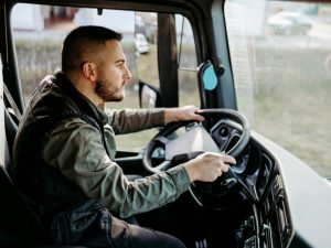 Truck driver steering through traffic while focusing on the road, reflecting the importance of a clean driving history.