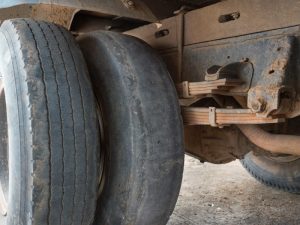 Close-up view of truck's worn-out tyres with visible damage, highlighting poor maintenance risks and road hazards.