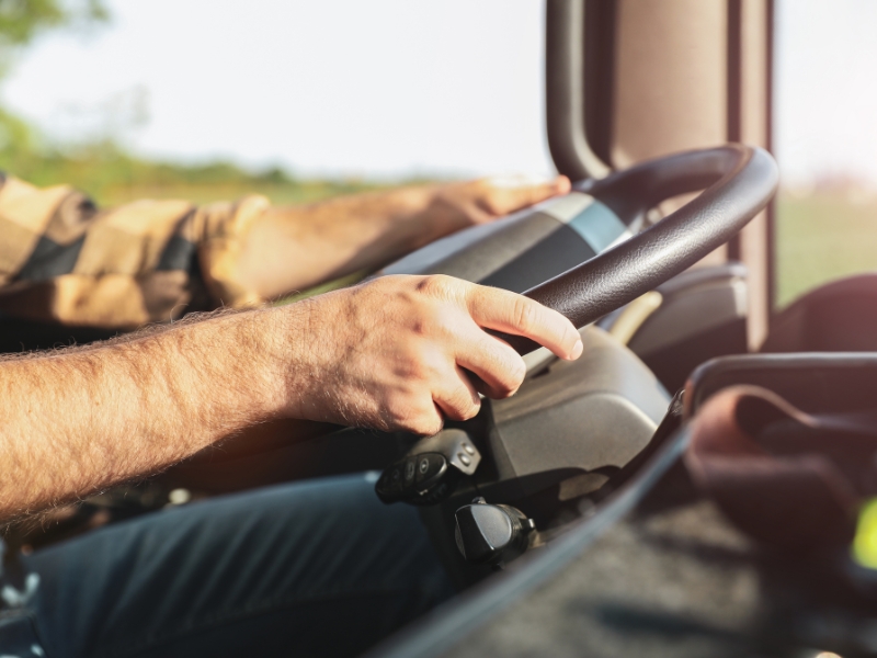 Driver gripping steering wheel during HR driving test practice inside heavy vehicle cabin.