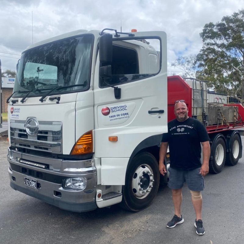 Smiling student beside HR Licence training truck at Core Driving School in NSW.