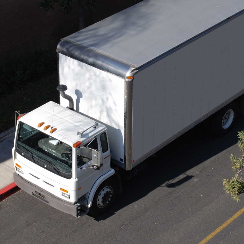 MR licence training truck: white medium rigid-style box truck parked along kerb, viewed from above in daylight.